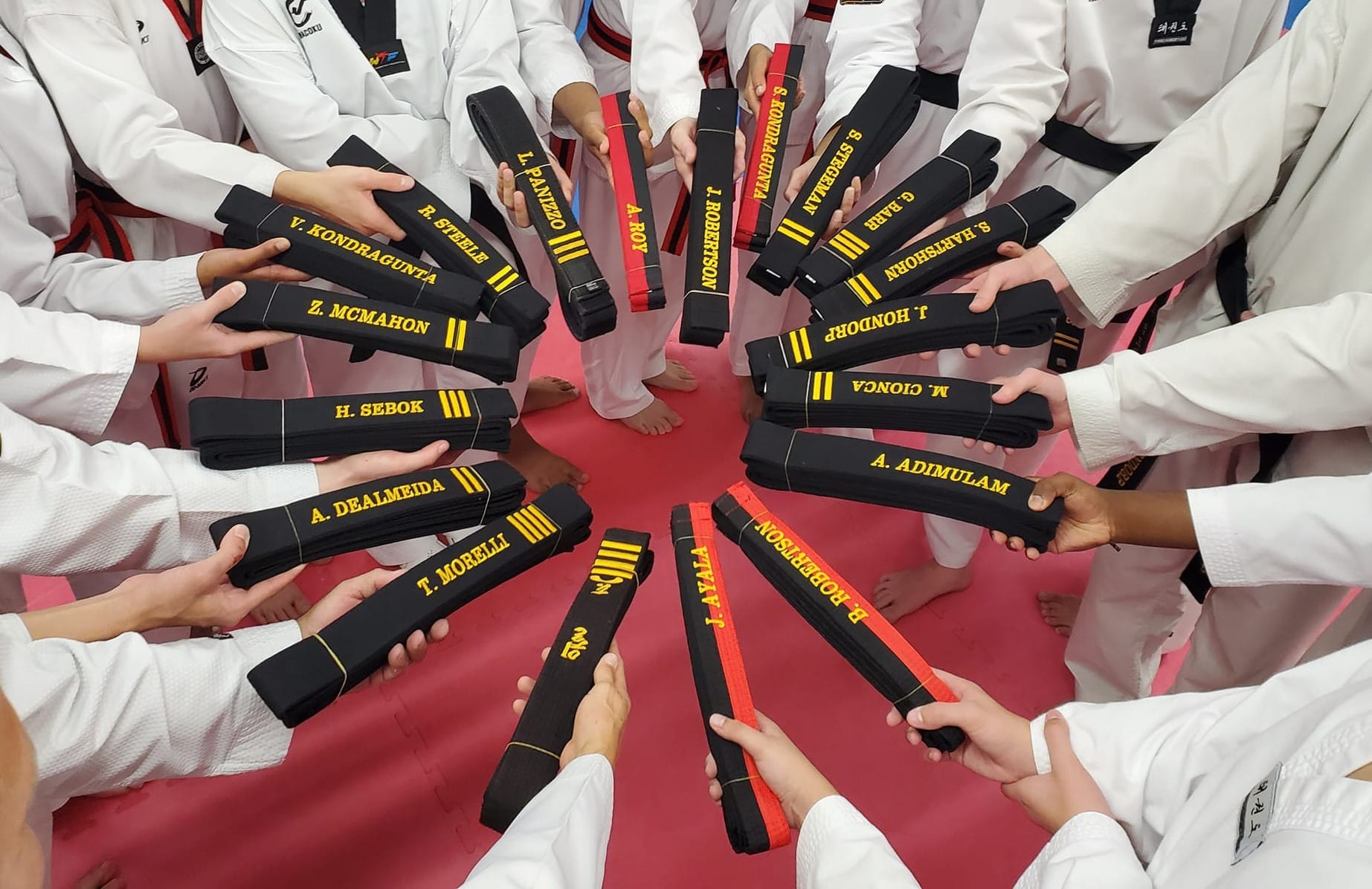 Midwest Tae Kwon Do close up of a circle of kids in gi holding black belts with names in a circle.