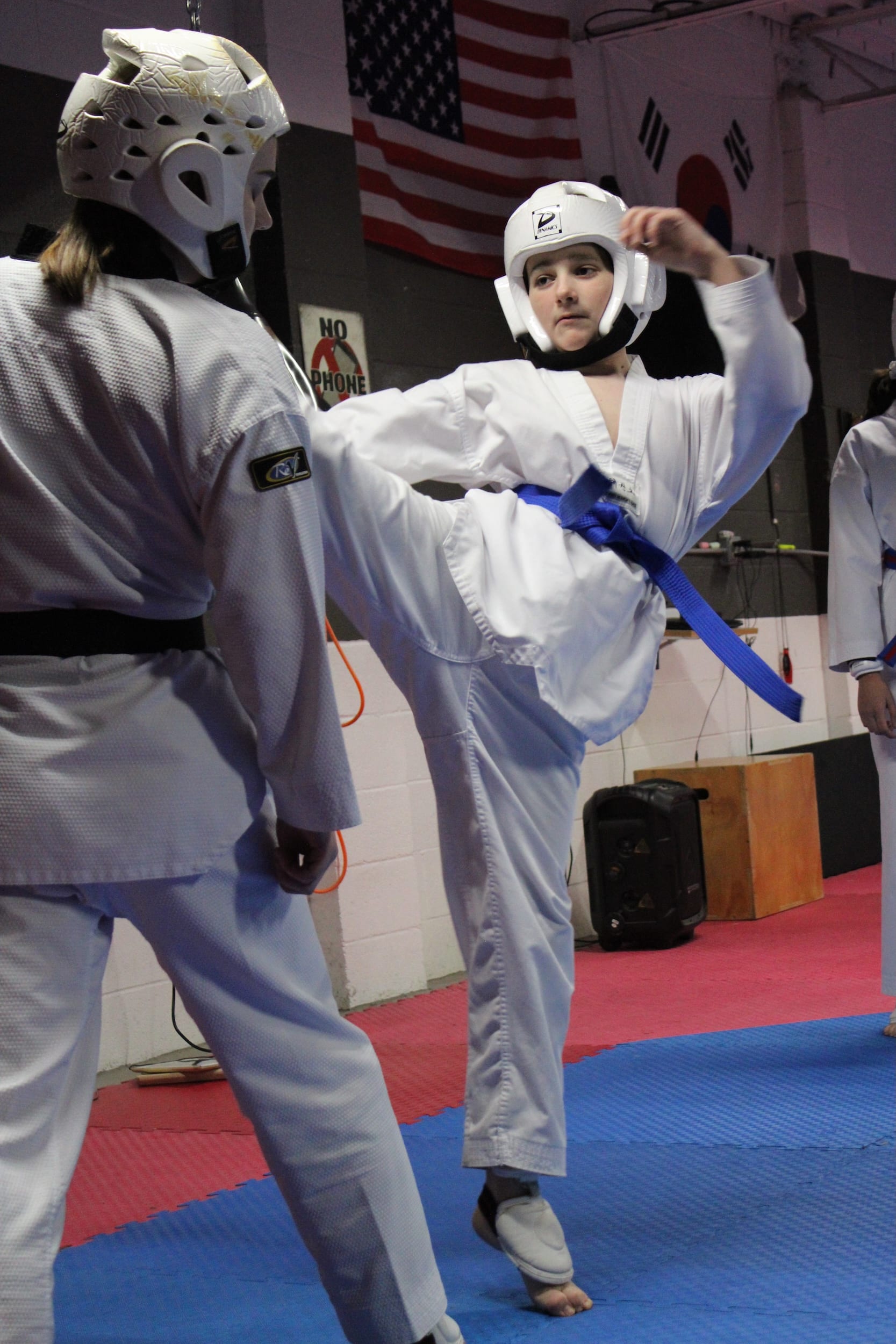 Midwest Tae Kwon Do teens in gi and gear sparring on the mat.